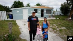 Alexis Llanos, izquierda, su pareja, Diomaris Barboza, y sus hijos Alexa, de 7 años, y Alexis, de 3, afuera de la casa a la que se mudaron en octubre de 2023, en Lehigh Acres, Florida, 27 de diciembre de 2023. (Foto AP/Rebecca Blackwell)