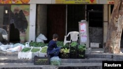 FILE - A boy sells vegetables and fruits along a street in the Damascus suburb of Qudsaya, Syria, July 24, 2017. 