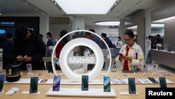 FILE - People look at Huawei Mate 60 series smartphones displayed at a Huawei flagship store in Beijing, Sept. 25, 2023.