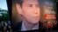 FILE - Women stand beside a poster of late prosecutor Alberto Nisman, marking the first anniversary of his death, in Buenos Aires, Argentina, Jan. 18, 2016.