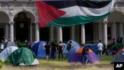 Estudiantes y activistas desenrollan una bandera palestina mientras instalan un campamento en el patio de la Universidad Statale en Milán, Italia, el viernes 10 de mayo de 2024. (Foto AP/Luca Bruno)