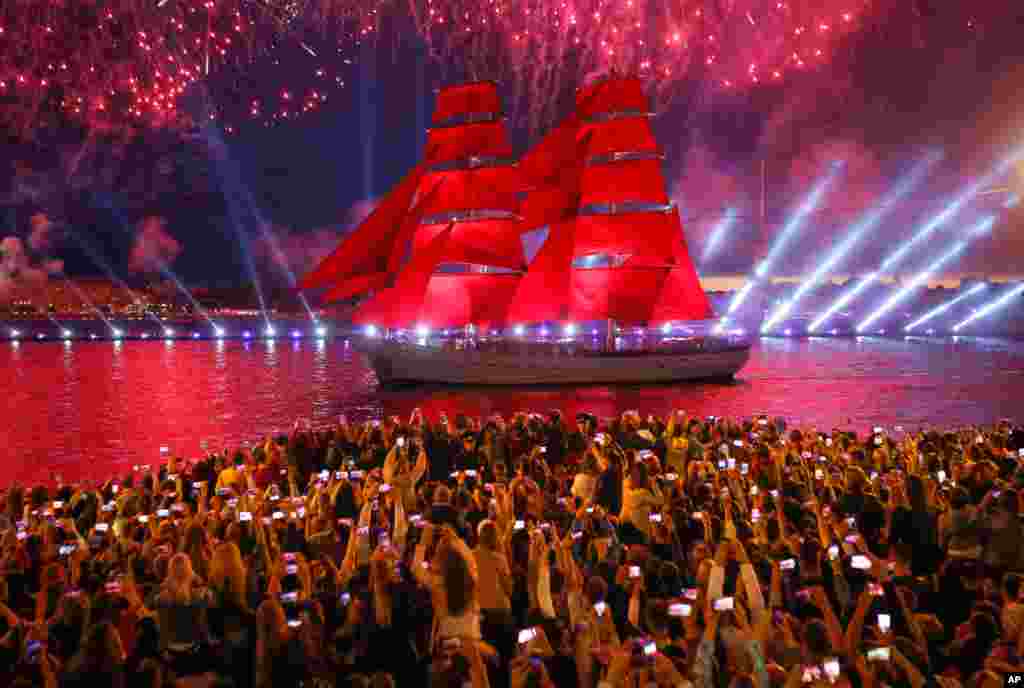 People watch fireworks and a brig with scarlet sails floating on the Neva River during the Scarlet Sails festivities marking school graduation in St. Petersburg, Russia.