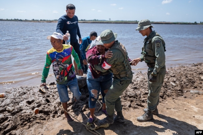 La gente llega a la costa de Puerto Guacara en La Paragua, estado Bolívar, Venezuela, el 23 de febrero de 2024, después del colapso de una remota mina ilegal. (Foto de Ronald PEÑA/AFP)