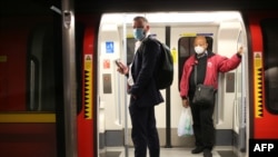 Para penumpang mengenakan alat pelindung diri, termasuk masker wajah untuk melindungi dari Covid-19 di kereta bawah tanah London, di Stasiun Waterloo, 11 Mei 2020. (Foto: AFP)