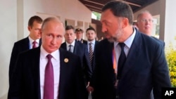 FILE - Russia's President Vladimir Putin, left, and Russian metals magnate Oleg Deripaska, right, attend the APEC Business Advisory Council dialogue in Danang, Vietnam, Nov. 10, 2017.