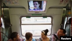 Los pasajeros del tren en Hong Kong escuchan noticias de que Snowden dijo al periodista Greenwald del diario The Guardia que no facilitó información a China ni a Rusia.