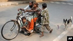 A beggar family commutes on a handcycle with their pet dog following on a leash in New Delhi, India, Saturday, Oct. 26, 2013. 