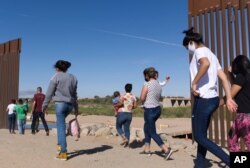 8일 미국 애리조나주 유마의 멕시코 접경에 세워진 국경장벽 사이의 틈으로 브라질 출신 불법이민자들이 걸어서 미국으로 입국하고 있다.