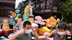 Visitors to the Yu Garden Mall put their masks on after posing for photos, June 2, 2022, in Shanghai. 