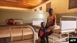 Une femme séjourne avec un enfant souffrant de malnutrition à l'hôpital de Kaabong à Kaabong, dans la région de Karamoja, en Ouganda, le 25 mai 2022.