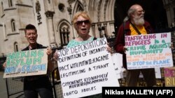 FILE: Demonstrators hold placards as they protest against Britain's Rwanda asylum plan outside the High Court in London on June 13, 2022.