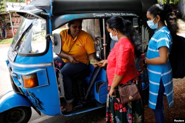 A passenger pays Lasanda Deepthi, 43, an auto-rickshaw driver for local ride hailing app PickMe, after they got dropped off at their destination in Gonapola town, on the outskirts of Colombo, Sri Lanka, May 25, 2022. (REUTERS/Adnan Abidi )