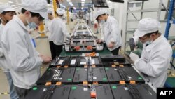 FILE - Workers at a factory for Xinwangda Electric Vehicle Battery Co. Ltd, which makes lithium batteries for electric cars and other uses, in Nanjing in China's eastern Jiangsu province, March 12, 2021.