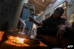 FILE - A woman prepares bread in her home at Zerzara village on the west bank of the Nile river, off of Egypt's southern city of Aswan, Feb. 26, 2022. Many fear Russia's invasion of Ukraine could mean less bread in Egypt, Lebanon, Yemen and elsewhere in the Arab world where millions already struggle to survive.