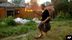 A woman runs from a house that's on fire after shelling in Donetsk, on territory under control of the Donetsk People's Republic, in eastern Ukraine, June 3, 2022.