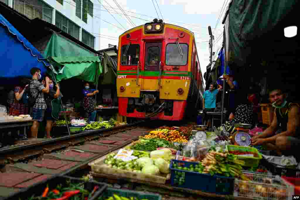 A passenger train passes through the Mae Klong railway market in Samut Songkhram province, around 80 kms (50 miles) southwest of Bangkok, Thailand, June 4, 2022.
