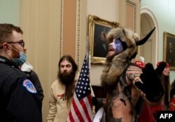 Pendukung Presiden AS Donald Trump, termasuk Jake Angeli (kanan), seorang pendukung QAnon yang dikenal dengan wajahnya yang dicat dan topi bertanduk, melakukan protes di US Capitol pada 6 Januari 2021, di Washington. (Foto: AFP)