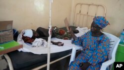 A woman fans a victim of St. Francis Catholic Church attack receiving treatment at St Louis Catholic Hospital in Owo Nigeria, June 6, 2022. Lawmakers in southwestern Nigeria say more than 50 people are feared dead after gunmen opened fire and detonated explosives at a church.
