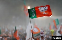 Seorang pendukung Partai Bharatiya Janata (BJP) yang berkuasa di India mengibarkan bendera partai selama kampanye pemilihan yang disampaikan oleh Perdana Menteri India Narendra Modi di New Delhi, India, 8 Mei 2019. (Foto: REUTERS/Adnan Abidi)