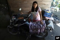 Abigail Pena, Esmeralda Dominguez's eldest daughter, poses for a photo with her mother's motorcycle, parked at their home in the Sisiguayo community in Jiquilisco, in the Bajo Lempa region of El Salvador, May 12, 2022.
