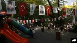FILE - People sit at Kugulu public garden decorated with national flags and images of Turkey's founder Mustafa Kemal Ataturk, in Ankara, Turkey, Thursday, June 2, 2022. (AP Photo/Burhan Ozbilici)