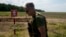 A Ukrainian soldier walks near a post warning about landmines in a field on the outskirts of Kyiv, June 9, 2022.
