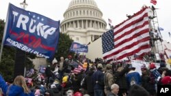 FILE - Violent insurrectionists loyal to President Donald Trump stand outside the U.S. Capitol in Washington on Jan. 6, 2021. The public hearings of the House committee investigating the insurrection pose a challenge to Democrats seeking to maintain narro