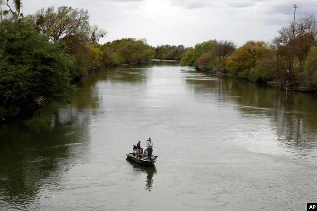 FILE - People fish in the Sacramento-San Joaquin River Delta's Elk Slough near Courtland, Calif., Tuesday, March 24, 2020. A proposal in the California state Senate aims to keep more water in California's rivers and streams to benefit endangered species of fish. (AP Photo/Rich Pedroncelli, File)