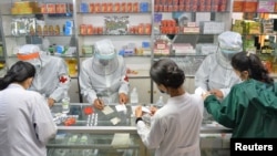 지난달 23일 북한 평양의 한 약국에서 방호복을 입은 군인들이 약국 직원들에게 의약품을 나눠주고 있다. KCNA via REUTERS.