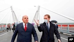 FILE - Russian Prime Minister Mikhail Mishustin, left, and Minister for the development of the Far East and Arctic Alexander Kozlov visit the bridge across the Amur River on the border between Russia and China in the city of Blagoveshchensk, Russia, Aug. 17, 2020. 