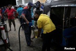 Lasanda Deepthi, 43, an auto-rickshaw driver for local ride hailing app PickMe, has a container filled with petrol during the early hours of the morning at a fuel station in Gonapola town, on the outskirts of Colombo, Sri Lanka, May 26, 2022. ( REUTERS/Ad