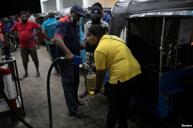 Lasanda Deepthi, 43, an auto-rickshaw driver for local ride hailing app PickMe, has a container filled with petrol during the early hours of the morning at a fuel station in Gonapola town, on the outskirts of Colombo, Sri Lanka, May 26, 2022. ( REUTERS/Ad