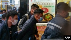 FILE - Stand News chief editor Patrick Lam (center) is brought to the news outlet's office building in handcuffs after police were deployed to search the premises in Hong Kong's Kwun Tong district on December 29, 2021.