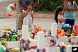 FILE - Mourners visit a memorial at Robb Elementary School, created to honor the victims killed in the recent school shooting, in Uvalde, Texas, June 6, 2022.