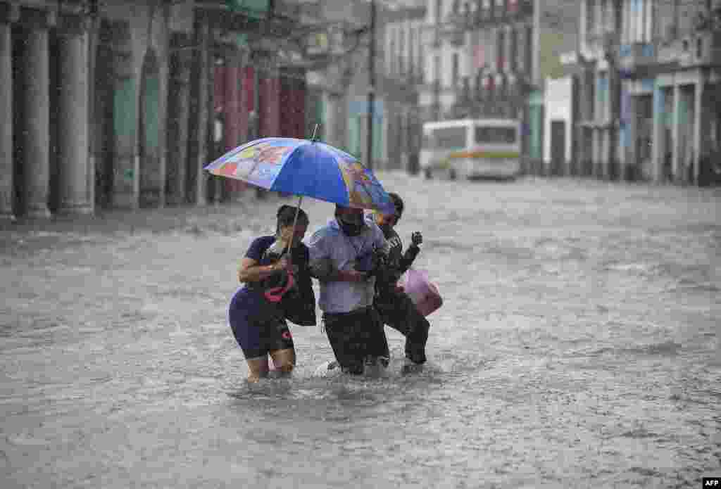 People wade through a flooded street of Havana, Cuba, following heavy rains in the island nation.