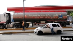 Un hombre tira de su auto junto a un camión de gasolina en una gasolinera en Caracas, Venezuela, el 14 de noviembre de 2020.