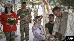 Ukrainian soldiers Kristina (no last name given), third-right, and Vitaliy Orlich, both 23, and Khrystyna Lyuta, left, 23, with Volodymyr Mykhalchuk, 28, get married in the town of Druzhkivka, in Ukraine's eastern Donetsk region, June 12, 2022.