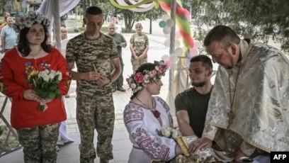 Ukrainian soldiers Kristina (no last name given), third-right, and Vitaliy Orlich, both 23, and Khrystyna Lyuta, left, 23, with Volodymyr Mykhalchuk, 28, get married in the town of Druzhkivka, in Ukraine's eastern Donetsk region, June 12, 2022.