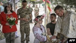 Ukrainian soldiers Kristina (no last name given), third-right, and Vitaliy Orlich, both 23, and Khrystyna Lyuta, left, 23, with Volodymyr Mykhalchuk, 28, get married in the city of Druzhkivka, in Ukraine's eastern Donetsk region, June 12, 2022.