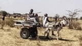 FILE: People use a donkey-pulled cart on June 30, 2021, to transport items left behind by the United Nations African Union Mission in Darfur (UNAMID), after withdrawal from Sudan's Darfur, underscoring the fragile security situation in a region of frequent tribal clashes. 