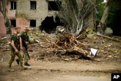 FILE - Ukrainian servicemen walk past a building heavily damaged in a Russian bombing in Bakhmut, eastern Ukraine, eastern Ukraine, May 28, 2022.