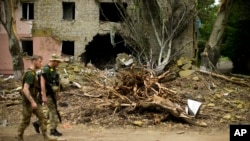 FILE - Ukrainian servicemen walk past a building heavily damaged in a Russian bombing in Bakhmut, eastern Ukraine, eastern Ukraine, May 28, 2022.