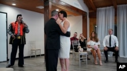 Charles King sings as Elvis as he marries Alicia Funk, center right, and Vaughan Chambers at A Little Wedding Chapel on May 12, 2020, in Las Vegas. (AP Photo/John Locher, File)