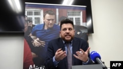FILE - Leonid Volkov, chief of staff for Russian opposition leader Alexey Navalny (background photo), speaks during an interview at the European Parliament in Strasbourg, France, on Dec. 14, 2021. Kremlin critic Navalny was jailed in February 2021.
