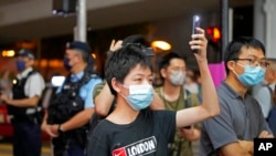 2022 年 6 月 4 日星期六，支持民主的抗议者在香港维多利亚公园附近手持发光的手机。