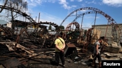 Workers inspect a damaged wood warehouse after a strike in the outskirts of Kharkiv, Ukraine, June 3, 2022.