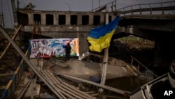 Мексиканський митець Роберко Маркез малює на зруйнованому мості в Ірпені у передмісті Києва. Фото зроблене 26 квітня 2022 року. AP/Еміліо Моренатті