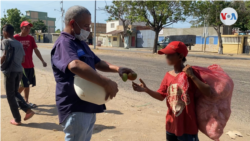 El activista social Oswaldo Díaz reparte mangos a niños, jóvenes y adultos que caminan por una avenida del sector Altos de Milagro Norte, en Maracaibo, Venezuela. [Foto: Gustavo Ocando, VOA]