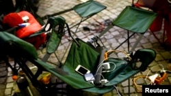 Power cords and battery chargers for Apple devices are seen on a foldable chair as people camp outside an Apple store in Franfurt, Germany. (FILE - REUTERS/Kai Pfaffenbach)