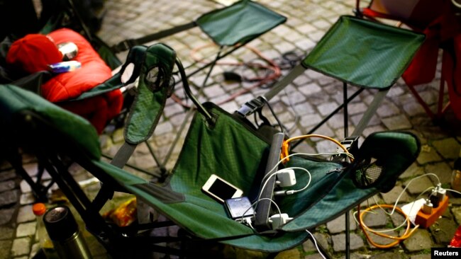 Power cords and battery chargers for Apple devices are seen on a foldable chair as people camp outside an Apple store in Franfurt, Germany. (FILE - REUTERS/Kai Pfaffenbach)